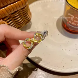 Detailopname van elegante goudkleurige gedraaide vierkante oorbellen met strass steentjes