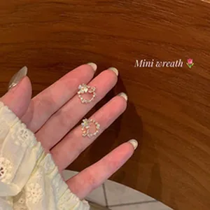 Detailed close-up view of elegant micro-pave floral wreath stud earrings held in hand