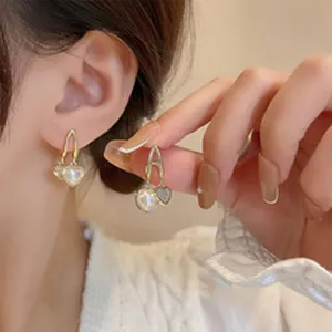 Detailed close-up showing elegant gold heart-shaped earrings with pearl and glitter
