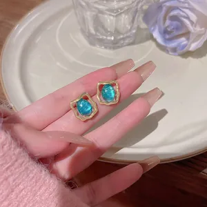 Close-up of retro S925 silver needle stud earrings with elegant blue stone settings.