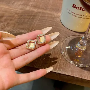 Close-up of elegant gold micro-paved square stud earrings with cat-eye stone