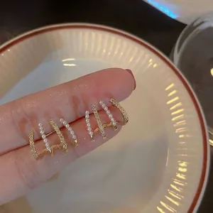 Detail of minimalist gold ear cuffs with pearls and sparkling pave stones.