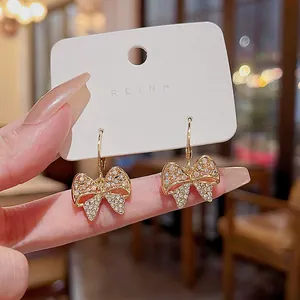Close-up detail of elegant gold bow earrings featuring micro-inlaid sparkling rhinestones