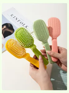 Detailed view of four colorful cactus-shaped folding air cushion hairbrushes held by hands