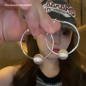 Detailed close-up of large silver hoop earrings with a single iridescent pearl bead