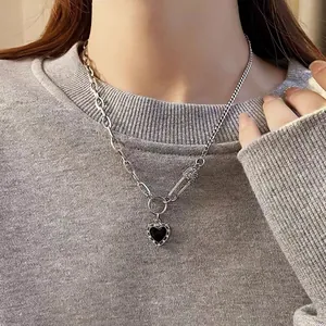 Detailed view of a silver titanium steel necklace with heart pendant worn on a grey sweater