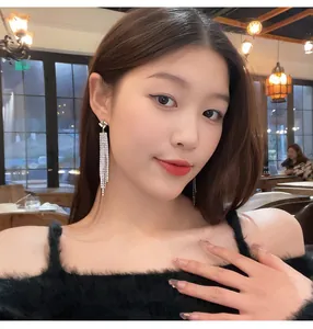 Elegant long tassel earrings with sparkling rhinestones worn by a model in a cozy cafe setting