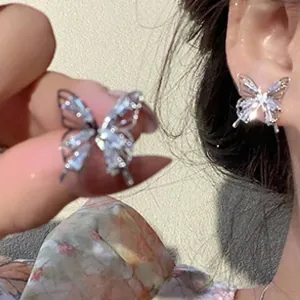 Close-up of sparkling crystal butterfly stud earrings worn on a model's ear