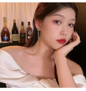Close-up of elegant 925 silver long tassel earrings with sparkling bow on Asian model.