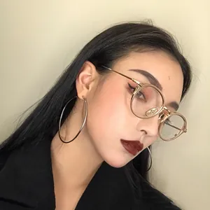 Model wearing oversized minimalist silver hoop earrings and gold round glasses