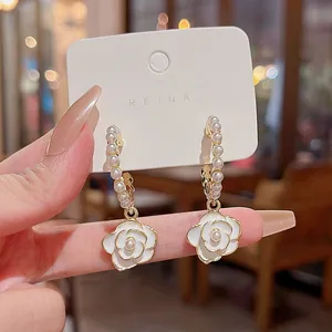 Detailed close-up of elegant white camellia flower drop earrings with pearl hoops