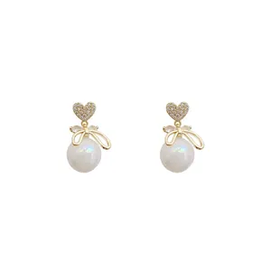 Elegant gold heart and pearl drop earrings with a delicate bow detail.