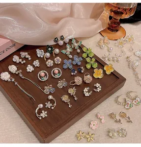 Elegant collection of floral and butterfly earrings displayed on a wooden tray.