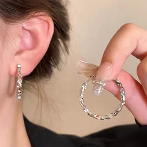 Detailed view of silver hammered hoop earrings worn by a model.