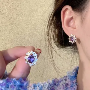Macro shot showcasing elegant purple zircon stud earrings with intricate floral design detail.