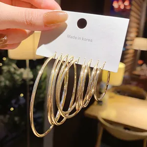 Macro view of golden minimalist hoop earrings in various sizes on a white card