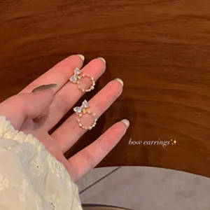 Close-up detail of elegant bow earrings featuring zircon and pearl hoop design