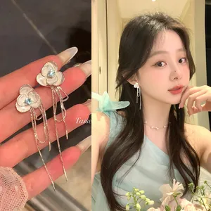 Elegant floral tassel earrings with blue zircon inlays shown on model.