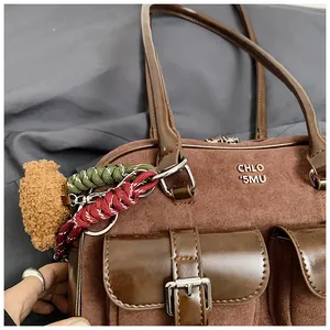 Vista detallada de un bolso bajo el brazo de ante marrón vintage con hebillas y dijes