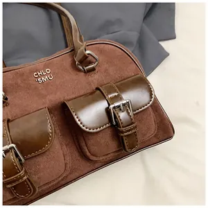 Detalle de un bolso de hombro vintage de ante marrón con dos bolsillos y hebillas