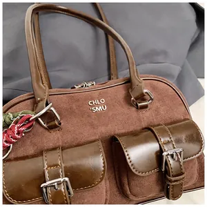 Primer plano de un bolso de hombro vintage de gamuza marrón con dos bolsillos