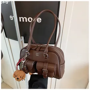 Primer plano de bolso sobaquero marrón vintage con múltiples bolsillos y llavero de perro