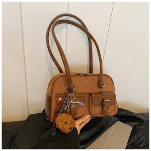 Detalle de bolso de hombro marrón vintage con bolsillos y dije de oso de peluche