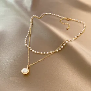 Detail of elegant double-layered vintage pearl necklace with gold-tone chain and pendant