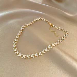 Detailed macro shot of vintage gold necklace with white pearls and crystals on silk background