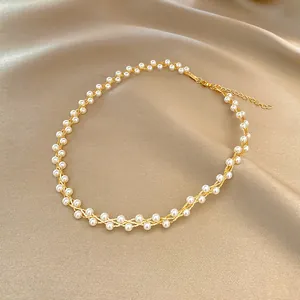 Elegant vintage gold wire wrapped pearl necklace displayed on luxurious champagne silk fabric