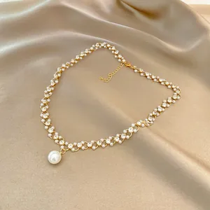 Detailed view of a vintage pearl and rhinestone necklace on champagne silk fabric.