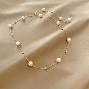 Elegant vintage gold chain necklace featuring round white pearls on silk background