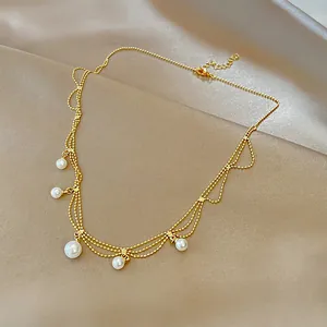Elegant gold layered necklace with vintage pearl drop pendants on silk background.