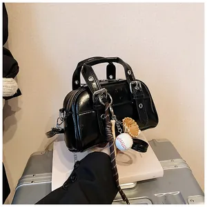 Vintage black glossy handbag with baseball charm on a silver suitcase background