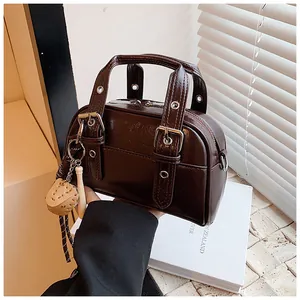 Vintage style dark brown handbag featuring buckle handles and baseball glove charm
