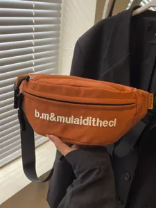Fashionable burnt orange crossbody waist bag featuring white embroidery and black strap