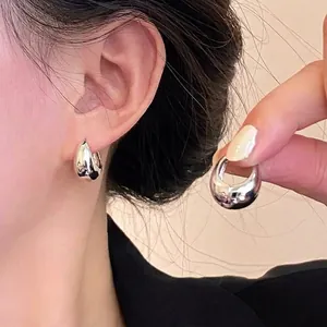 Detalle de pendientes de aro plateados brillantes usados por una modelo muy elegante.