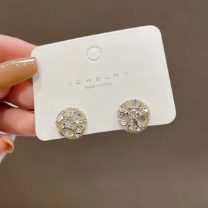 Primer plano de pendientes magnéticos brillantes con cristales en tarjeta blanca