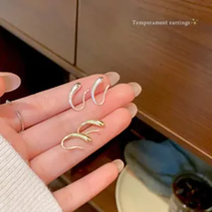 Detailed view of elegant silver and gold waterdrop hook earrings held in hand.