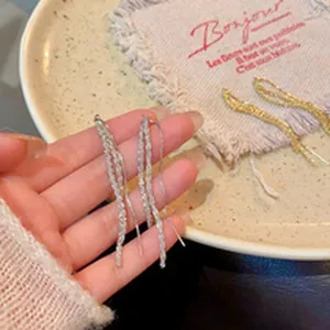 Detailed macro view of silver and gold twist metal tassel dangling earrings on a plate