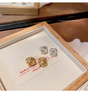 Detailed close-up of gold and silver twisted knot metal earrings on a tray
