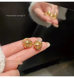 Detailed view of gold twisted metal knot earrings with elegant mirror reflection
