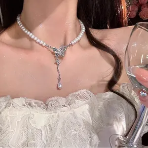Close-up of a butterfly pendant on a pearl necklace worn by a model in a luxury setting