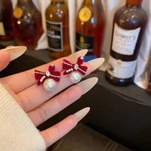 Close-up shot showing detailed red velvet bow earrings with elegant pearl dangles
