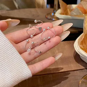 Detailed macro view of silver star and ball spiral stud earrings held on a hand palm.