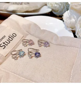 Close-up detail of silver-tone ear cuffs featuring vibrant pink and blue zircons