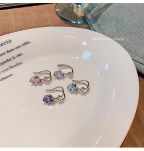 Set of four sparkling cubic zirconia ear cuffs in various colors on a white plate