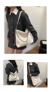 Detailed view of a cream pleated tote bag with silver chain decoration worn by model