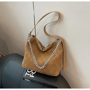 Detailed view of brown pleated tote bag featuring silver chain accent and leather strap