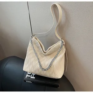Detail view of cream pleated tote bag with silver chain and shoulder strap